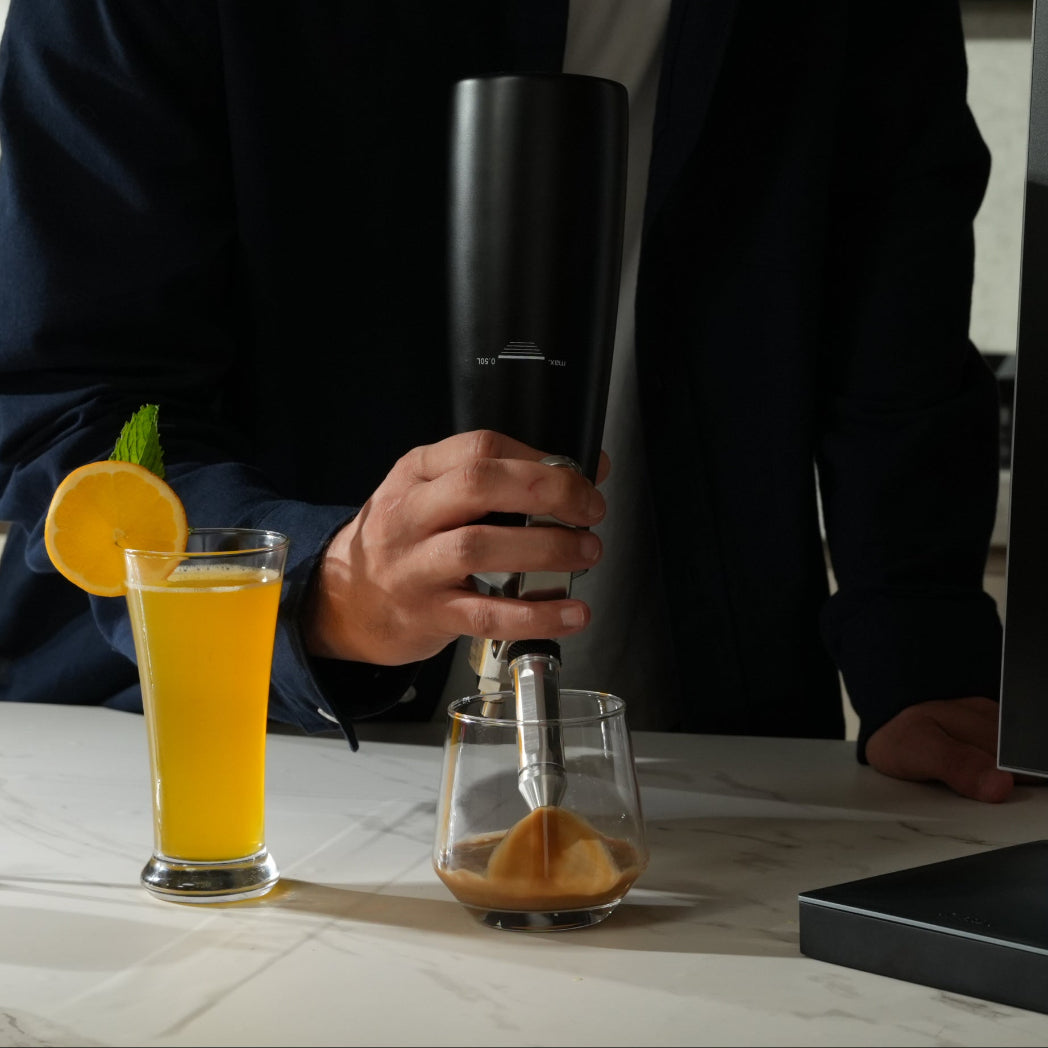 Man preparing a drink in a kitchen with a nitro machine and various drinks on the counter.